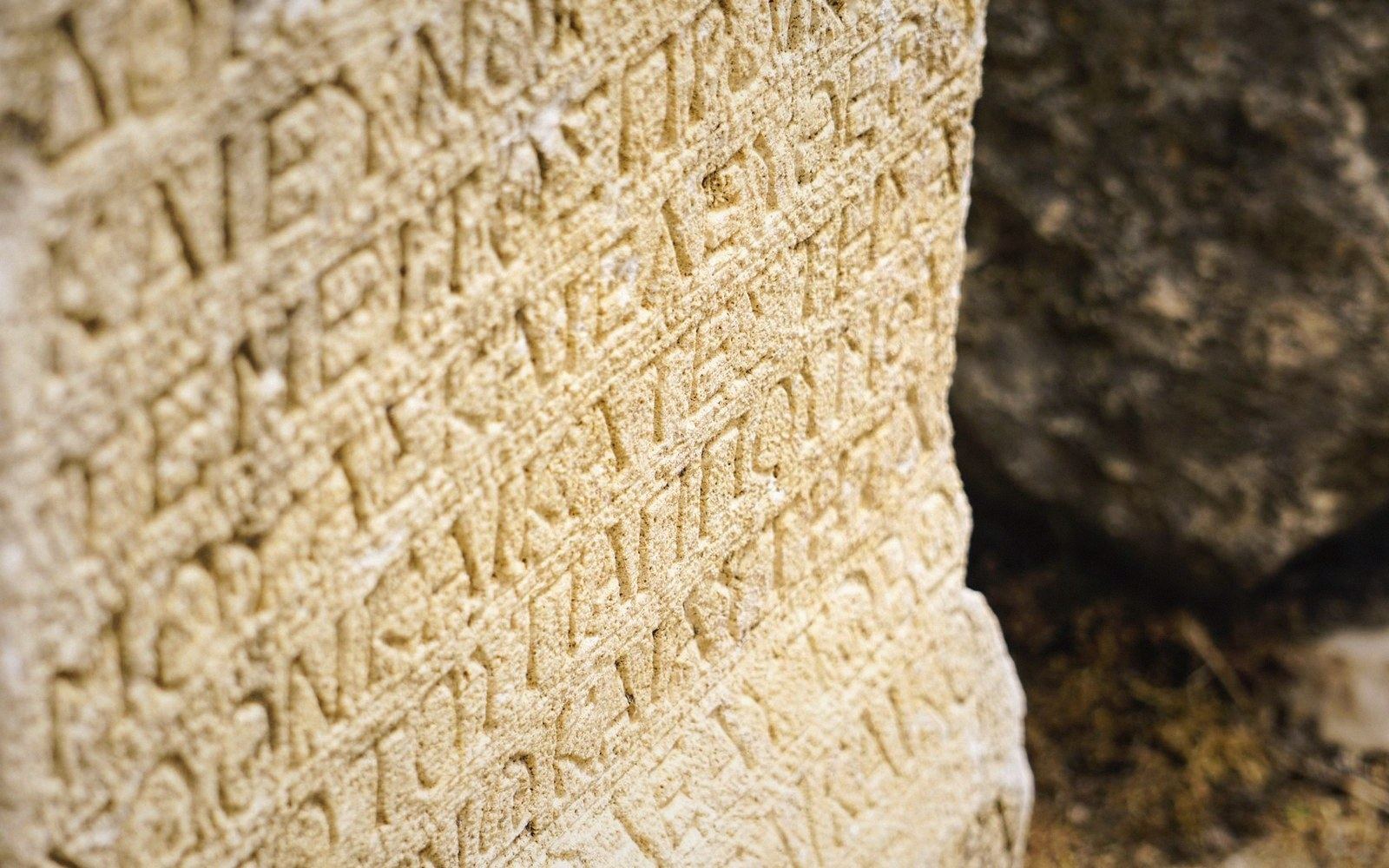 Close-up of ancient carved lettering running in rows across a stone surface