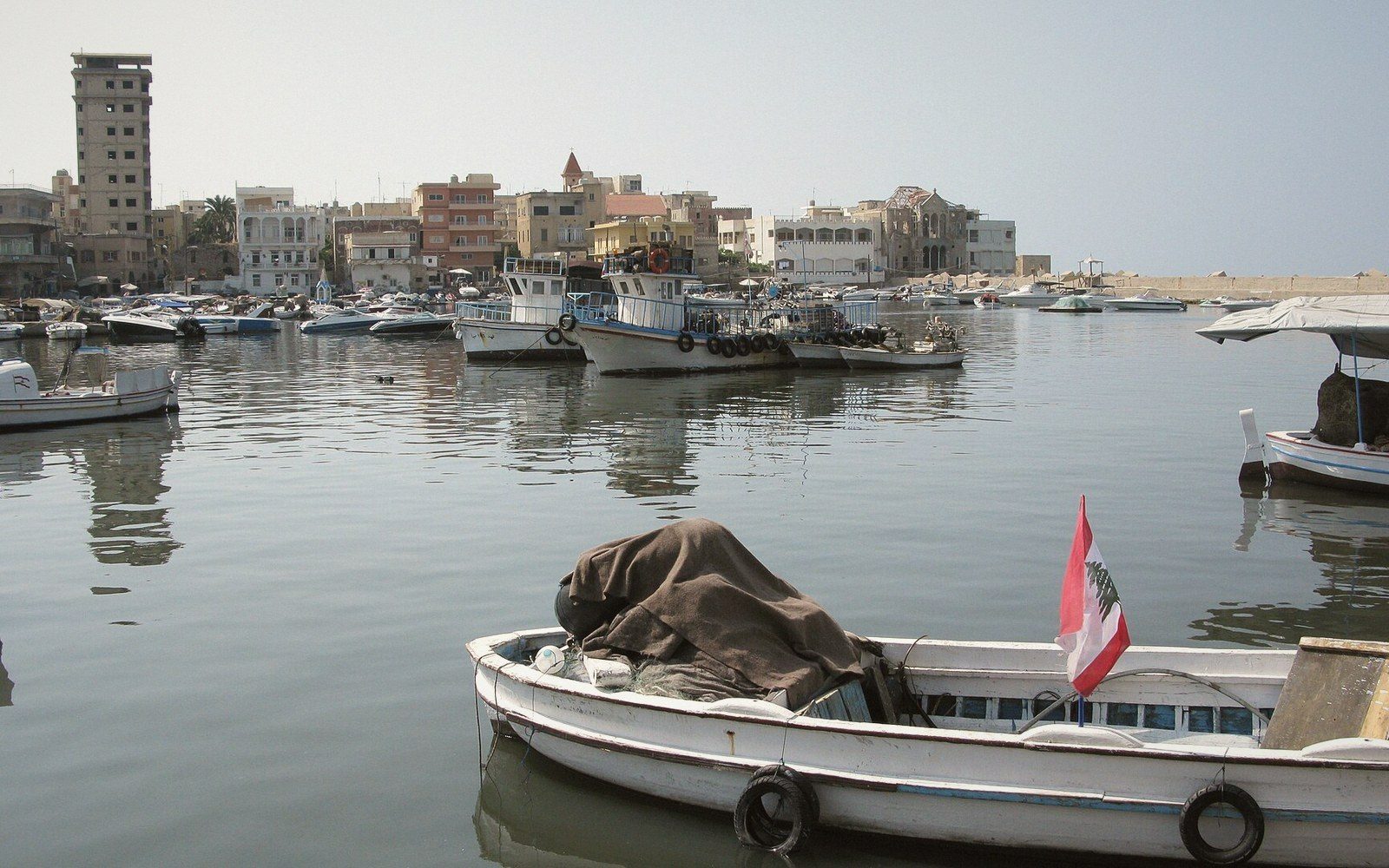 Fishing boats moored in Tyre's harbour with a Lebanese flag on the nearest vessel