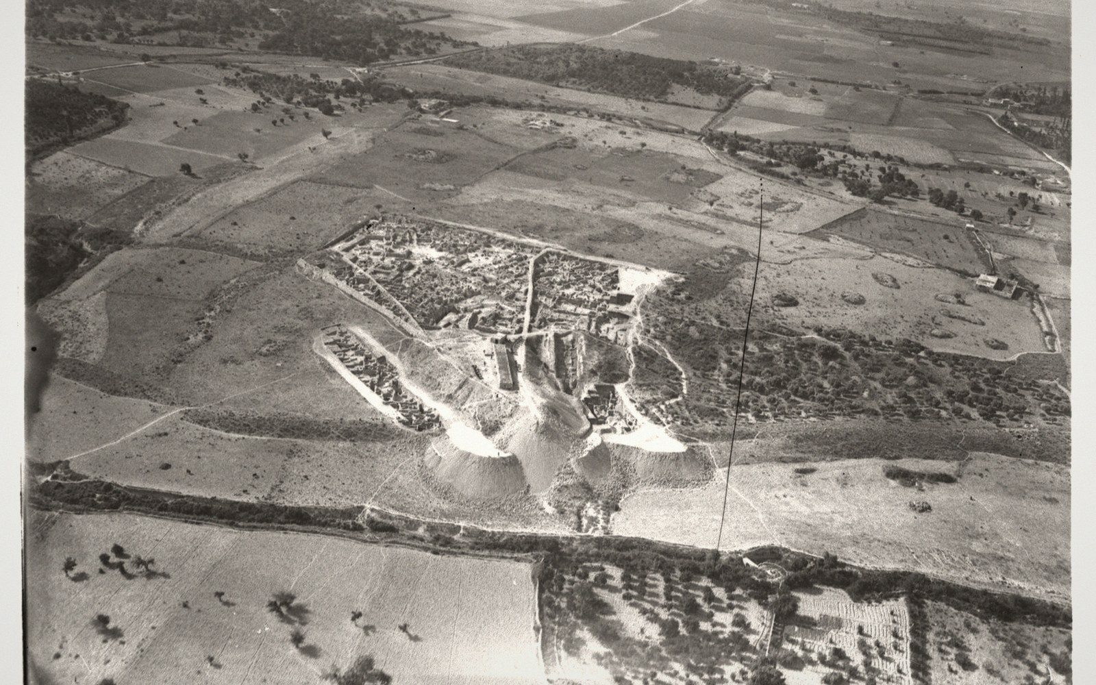 Aerial view of the Ras Shamra mound rising above surrounding farmland and fields