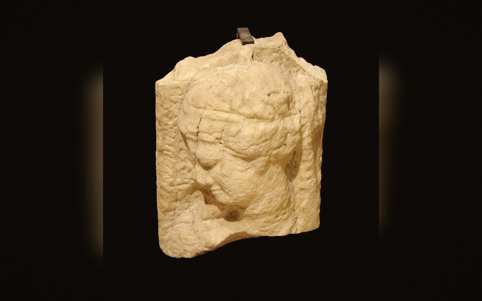 Carved alabaster fragment showing a bowed human head in profile relief